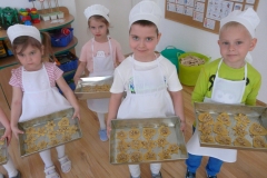 dzieci stoją z blaszkami pełnymi ciasteczek