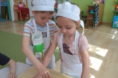 dzieci wykrawają foremkami ciasteczka