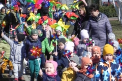 dzieci idą z wiatraczkami i wstążkami